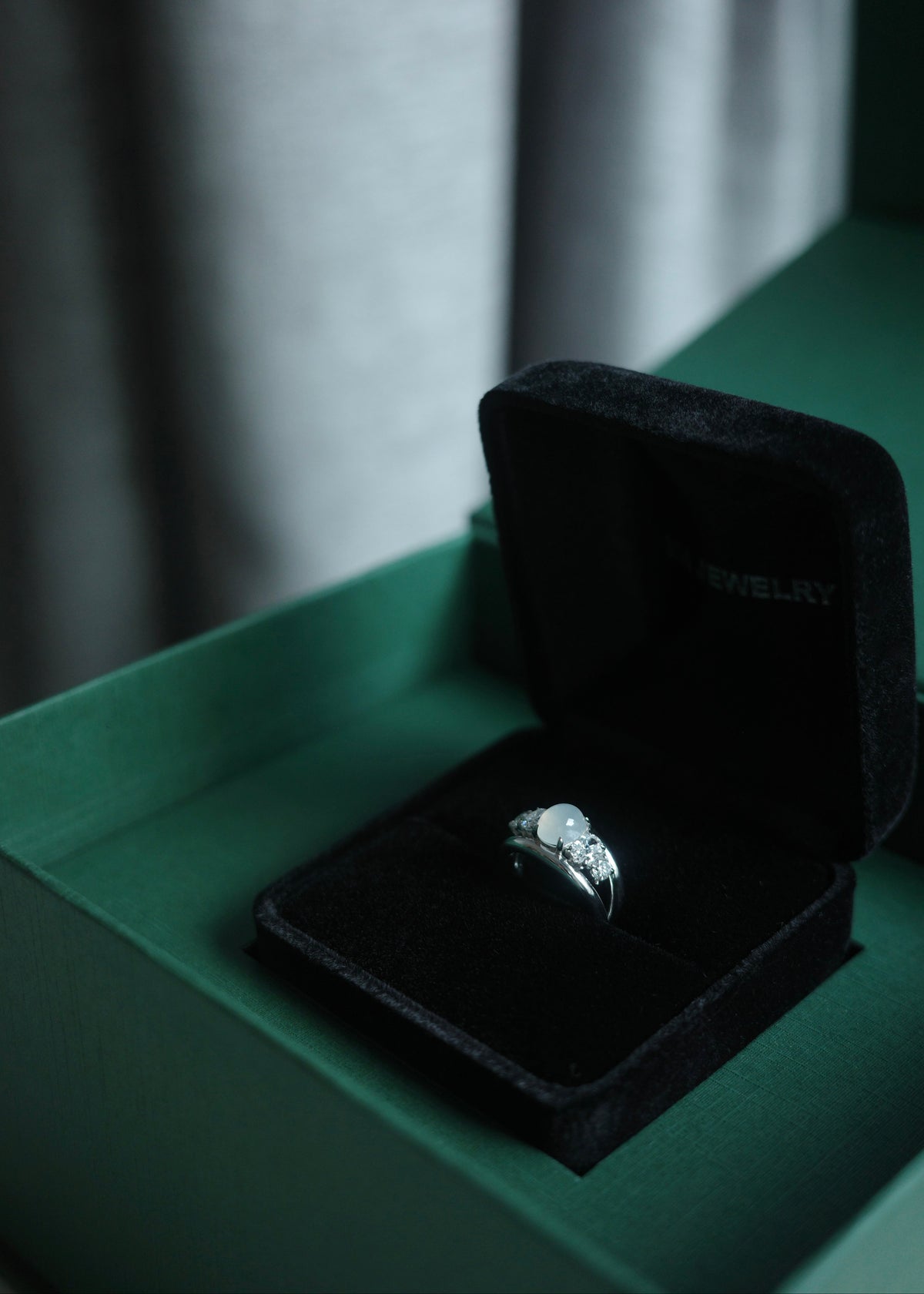 Icy white jadeite and diamond ring displayed in HN Jewelry signature luxury green box.
